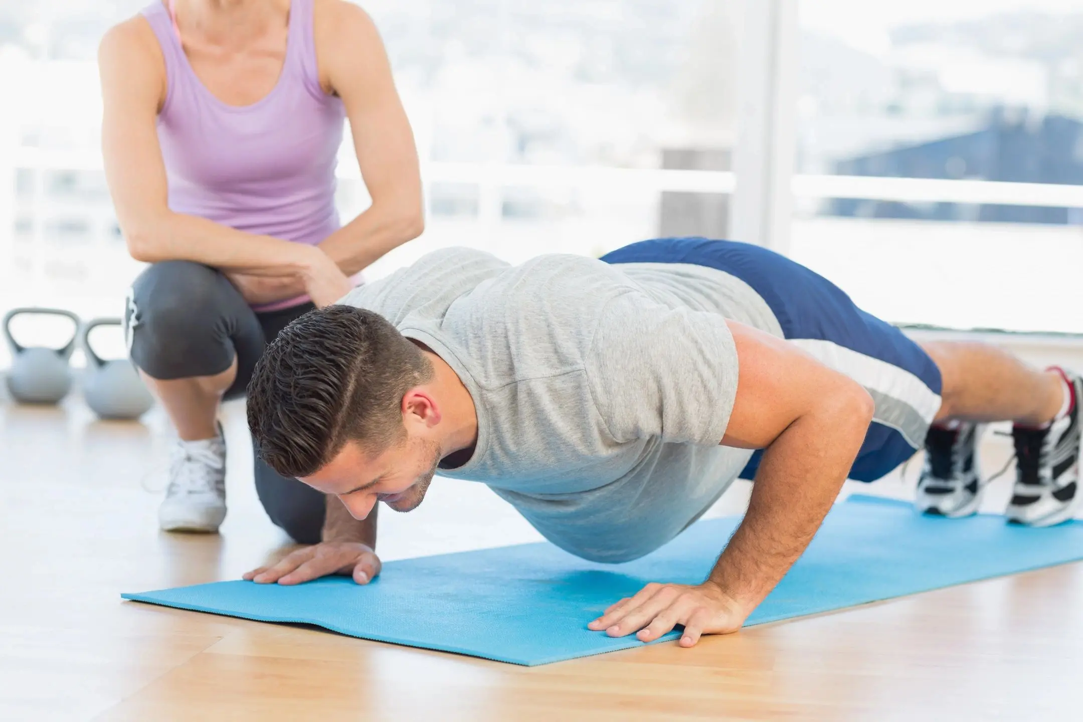 qtq80-n9RIVD A man doing push ups on top of a blue mat.